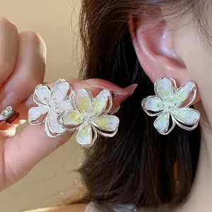 Close-up of elegant floral stud earrings with silver needles and glitter enamel finish