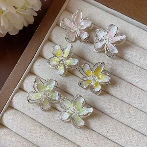 Detailed macro shot of three pairs of flower enamel earrings in pastel colors