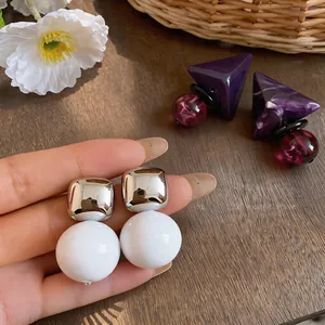 Primo piano dettagliato di orecchini a perno in resina quadrati e rotondi argento e bianco.