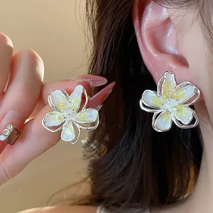 Close-up of elegant flower ear studs with yellow and white enamel oil drip texture