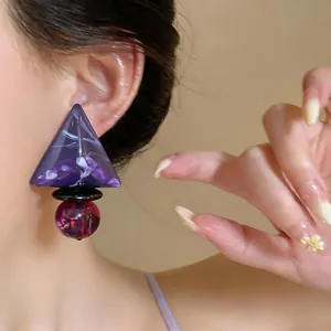 Dettaglio macro di un orecchino geometrico in resina viola con un esclusivo motivo marmorizzato