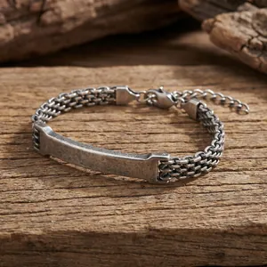Close-up of vintage stainless steel mesh bracelet with curved ID plate on wood