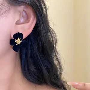 Elegant black velvet flower stud earring with gold stamen on model close-up detail view