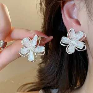 Detailed view of elegant pearlescent white flower stud earrings with a silver-tone finish
