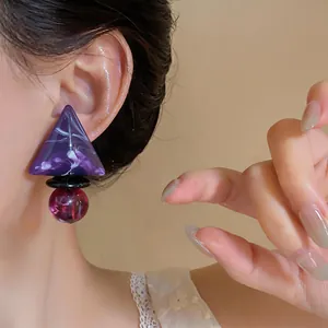 Primo piano dettagliato di un orecchino geometrico in resina con perle viola marmorizzate viola