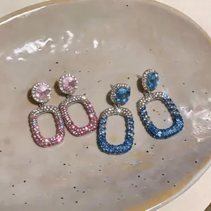 Close-up of elegant rhinestone hollow drop earrings with blue and pink crystals.
