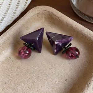 Vista macro di orecchini geometrici in resina viola con pendenti marmorizzati