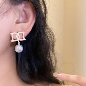 Detail shot of a vintage French style pearl drop earring worn on ear, gold finish.