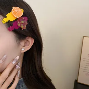 Détail de jolies barrettes en résine avec motifs d'orange et de fruit du dragon