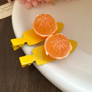Détail de barrettes à cheveux mandarine en résine avec base bec de canard jaune.
