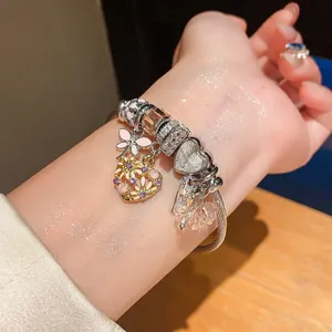 Nahaufnahme eines Vintage-Bettelarmbands mit Libellen- und Herzanhängern am Handgelenk