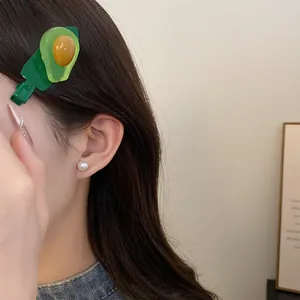 Gros plan d'une pince à cheveux douce en résine avocat portée sur les cheveux d'un modèle