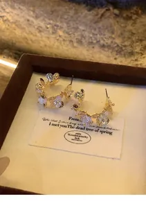 Detailed macro view of elegant gold C-shaped flower earrings featuring sparkling zircons