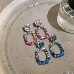 Detailed view of hollow geometric earrings with pavé-set pink and blue rhinestones