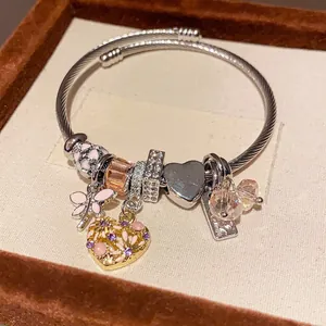 Detailansicht eines Vintage-Charm-Armreifs mit Libellen- und Herzanhängern im Etui.