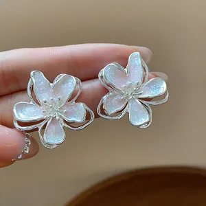 Close-up detail of elegant white sparkly flower-shaped stud earrings with silver borders