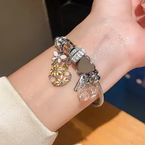 Detailansicht eines silbernen Bettelarmbands mit rosa Libellen- und Herzanhängern