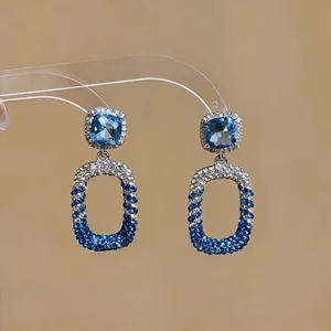 Close-up of elegant blue and silver crystal encrusted oval dangling drop earrings