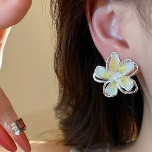 Detailed macro shot of elegant yellow enamel flower stud earrings for a chic look