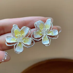 Elegant flower stud earrings with yellow enamel glitter and silver needle design.