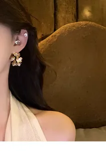 Close-up of zircon pleated flower stud earrings on model's ear