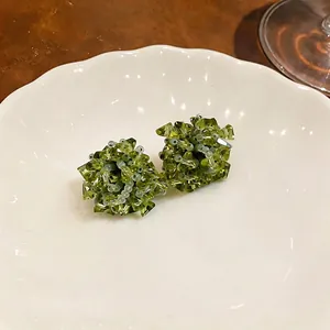 Handmade forest style green glass bead cluster stud earrings presented on a ceramic plate