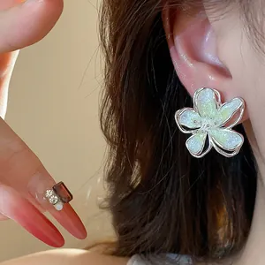 Macro view of elegant flower stud earrings with shimmering light green enamel petals