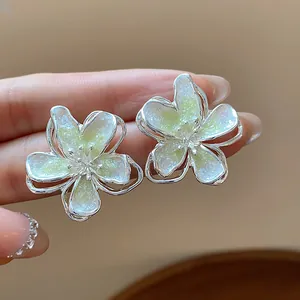 Close-up of elegant flower stud earrings with shimmering yellow enamel and silver finish