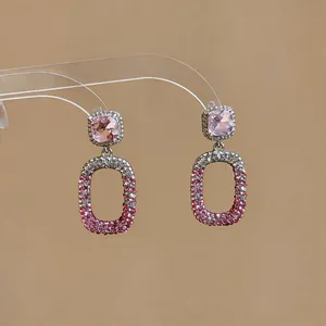 Close-up of elegant pink crystal drop earrings with silver pavé stones and square gems