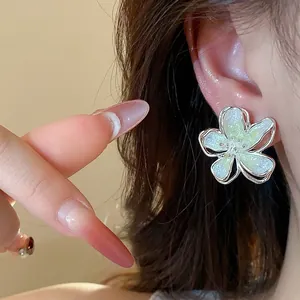 Close-up view of elegant pale green gradient flower stud earrings with a shimmer finish