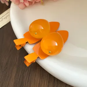 Gros plan de barrettes à cheveux en résine en forme de fruit avec clips orange