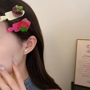 Gros plan sur des barrettes à cheveux en résine avec mangoustan et fraise sur un modèle