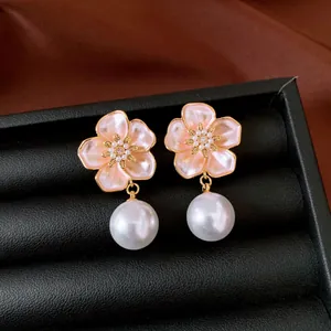 Detailed close-up of pink enamel flower earrings featuring elegant large white pearl drops