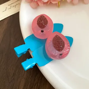 Détail de jolies pinces à cheveux en résine rose en forme de fruit avec clips bleus.
