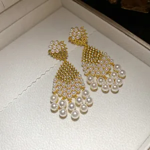Detail view of elegant gold drop earrings with pearls and shimmering zirconia stones