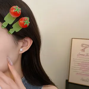 Vue détaillée de jolies barrettes en résine rouge en forme de tomate portées sur le côté