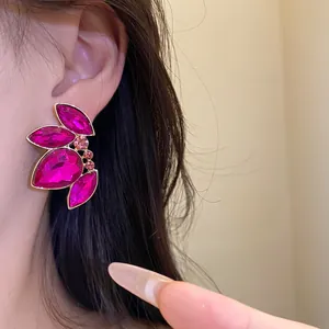 Primer plano detallado de aretes grandes de cristal fucsia en elegante montura dorada