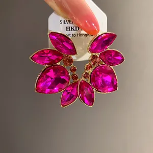 Vista detallada de los pendientes de strass fucsia con montura floral dorada
