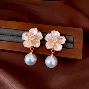 Detailed close-up of French retro floral earrings with pearl drops on wooden display stand