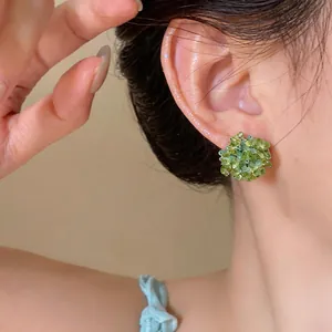 Detailed close-up showing green beaded flower stud earrings with S925 silver needles on ear