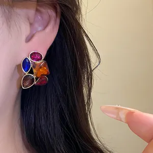 Primer plano de pendientes vintage con gemas de colores en la oreja de una modelo asiática