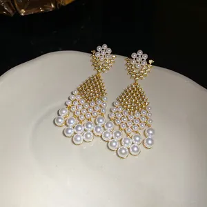 Detailed macro shot of elegant gold-toned pearl drop earrings with zircon stones.