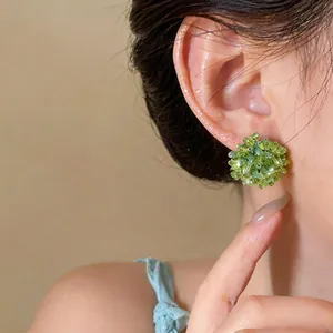 Close-up of green handcrafted beaded flower stud earring on an Asian woman's ear