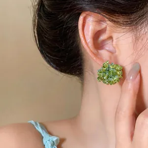 Close-up showing the elegant wearing effect of green glass flower stud earrings