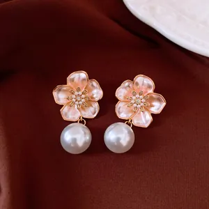 Detailed close-up of elegant vintage flower earrings with pink enamel and pearl drops.