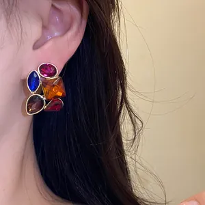Primer plano de pendientes cuadrados vintage con cristales multicolores en modelo