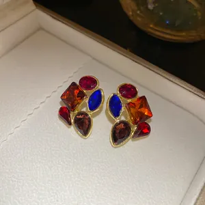 Vista macro de pendientes vintage dorados con cristales de piedras preciosas facetadas de colores