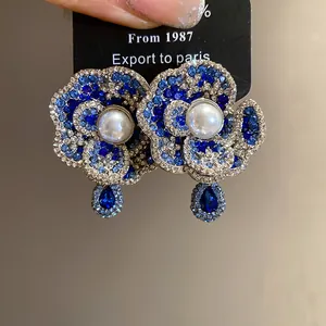 Detail of vintage flower earrings featuring blue gradient rhinestones and center pearl.