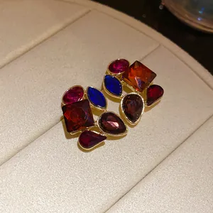 Vista detallada de pendientes vintage cuadrados con gemas de colores y acabado dorado