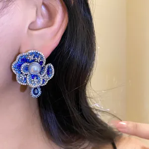 Close-up of vintage blue rhinestone flower earrings with pearl on a female model's ear